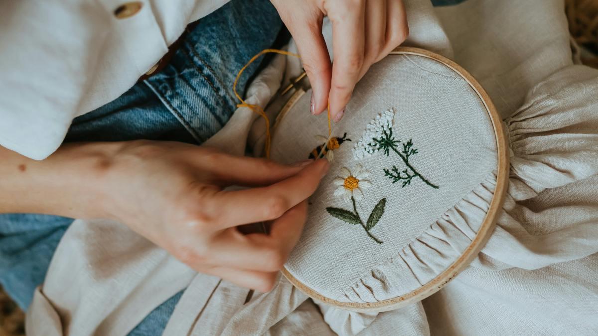 
a woman is stitching a flower on a pillow
