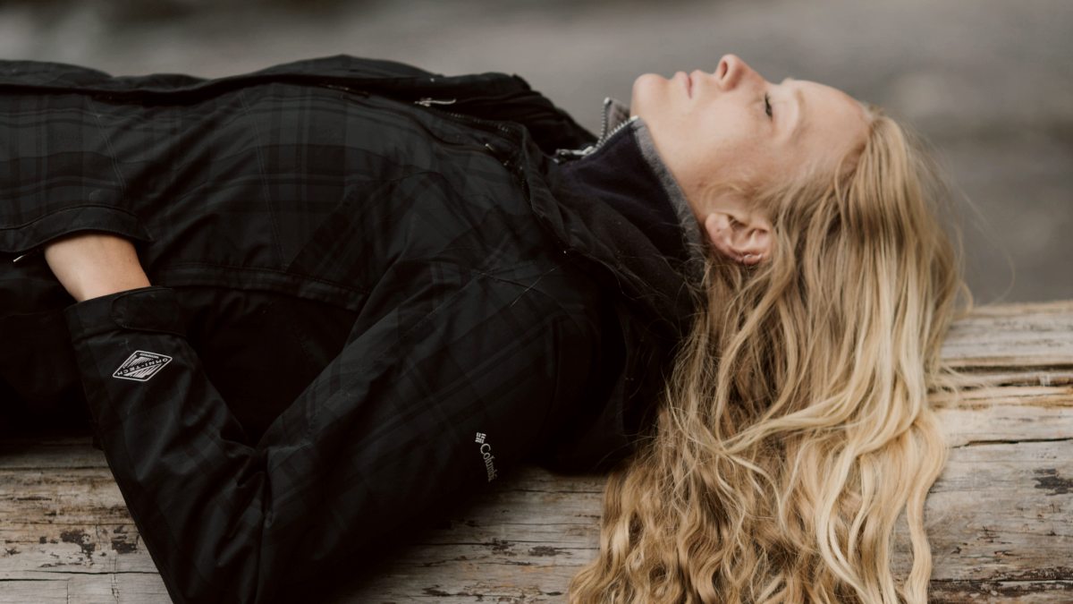 
a-woman-laying-down-on-a-fallen-tree-trunk
