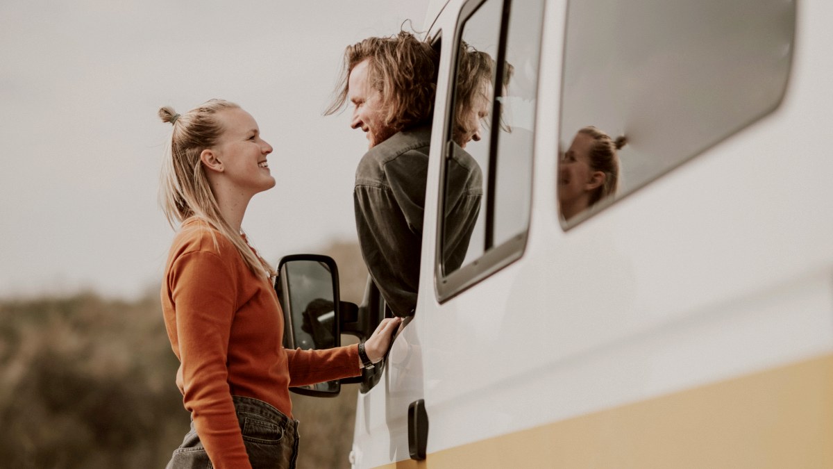 
a woman looking at her partner as he sits in his van
