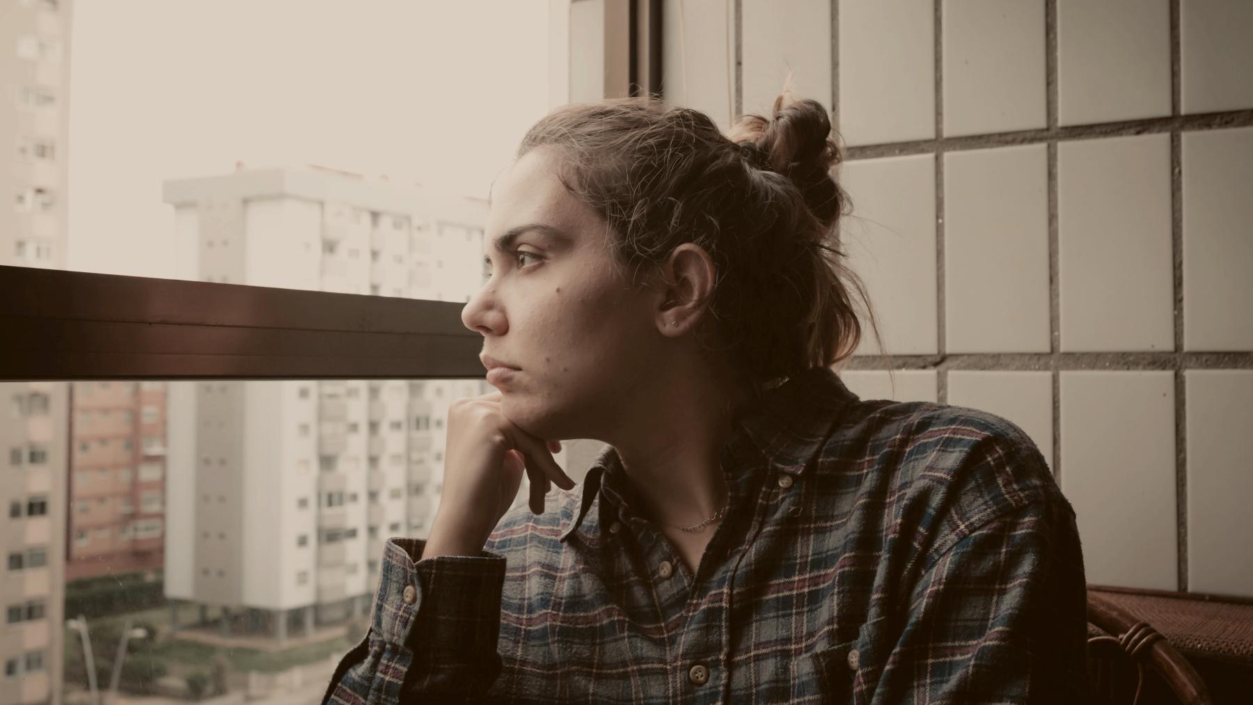 
a woman looking out a window at a city by A. C.
