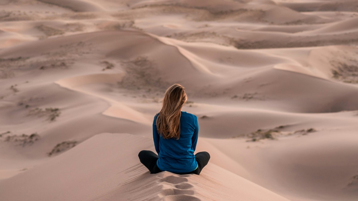 
a-woman-practicing-mindfulness-meditation-on-a-dune
