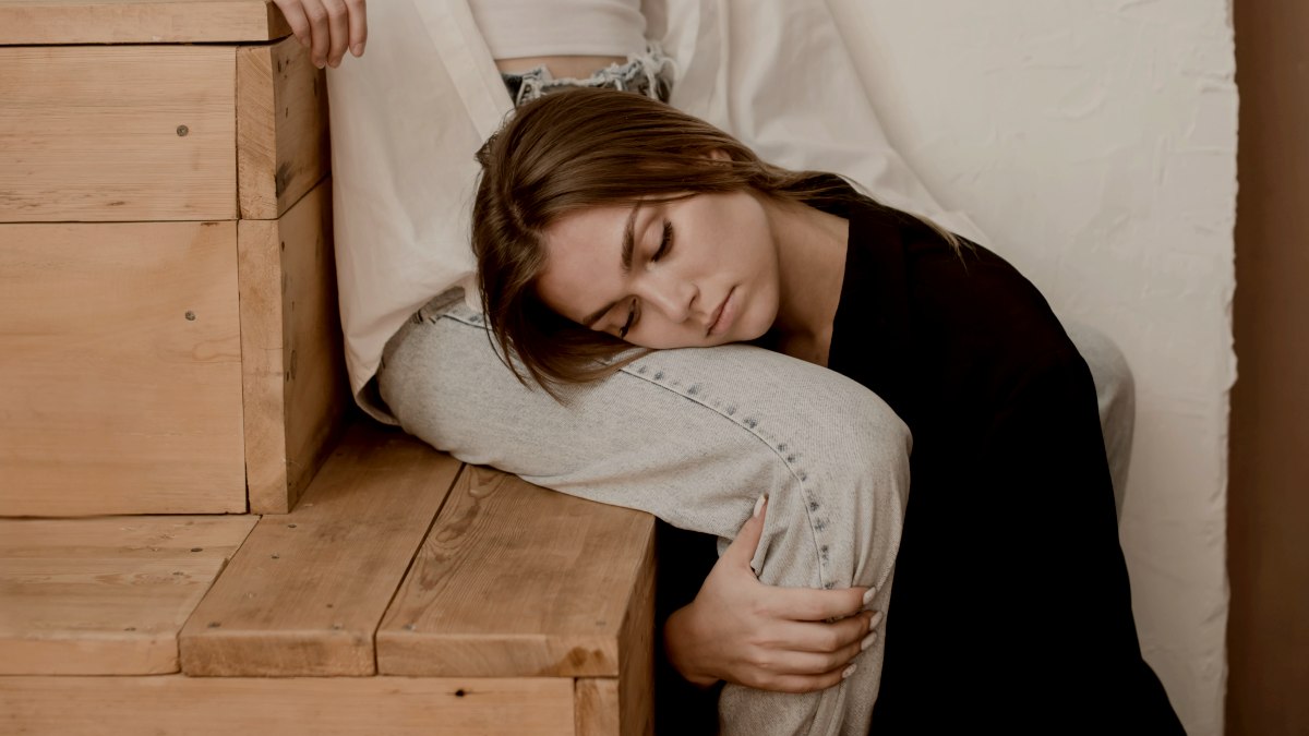 
a woman resting her head on her partners leg
