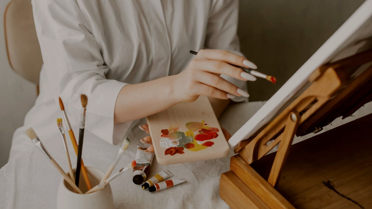 
a woman sitting at a table with a brush and palette
