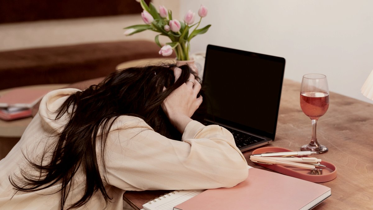 
a woman sitting at a table with a laptop and a glass of wine by Mushaboom Studio
