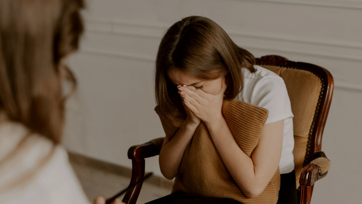 
a woman sitting in a chair with her hand on her face
