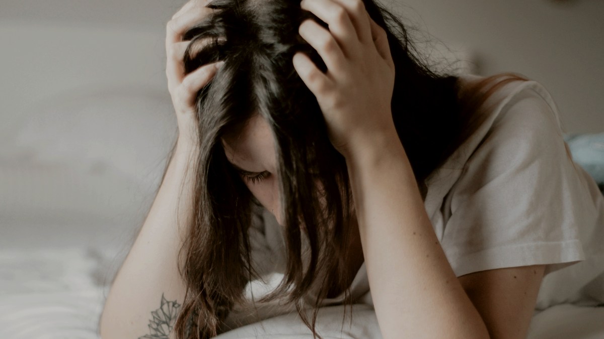 
a-woman-sitting-on-a-bed-with-her-head-in-her-hands
