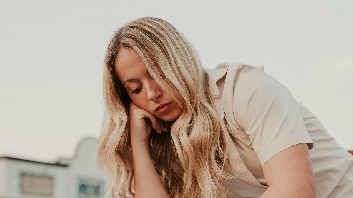 
a woman sitting on a chair in a parking lot with her head in her hands
