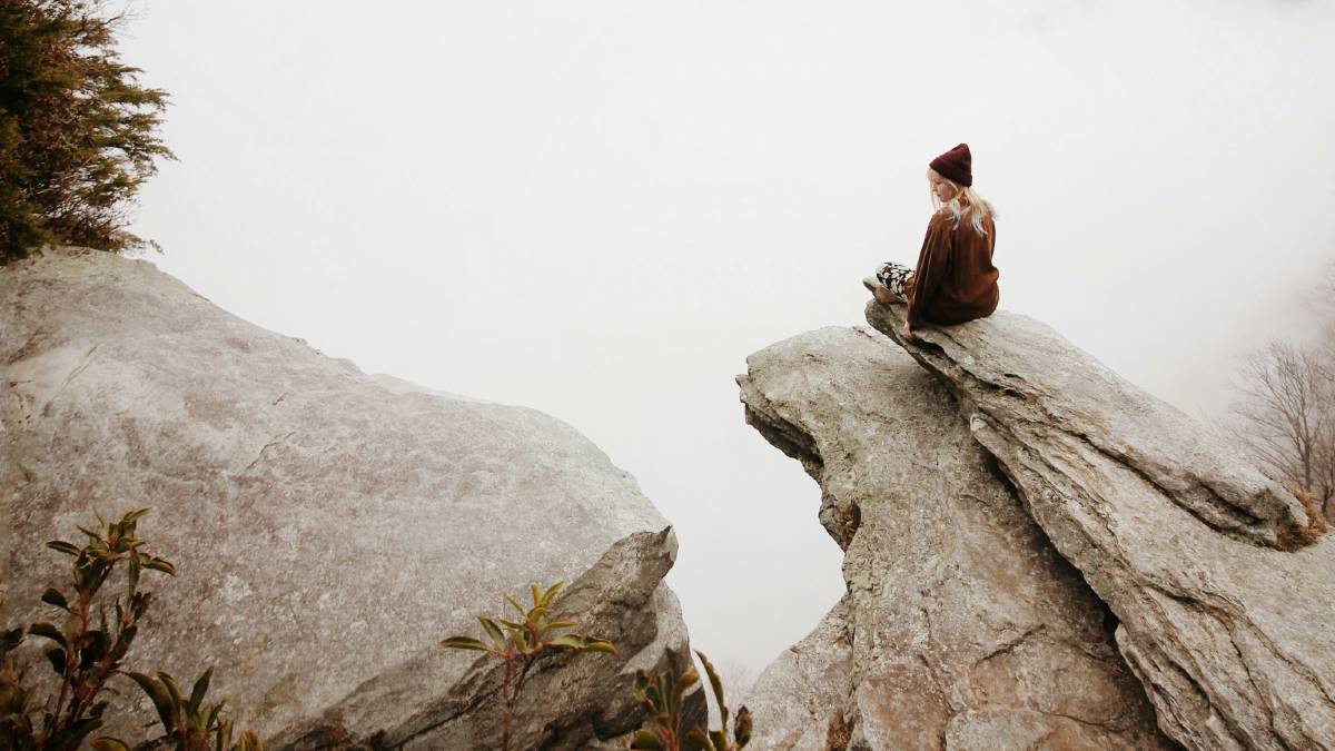 
a-woman-sitting-on-a-cliff
