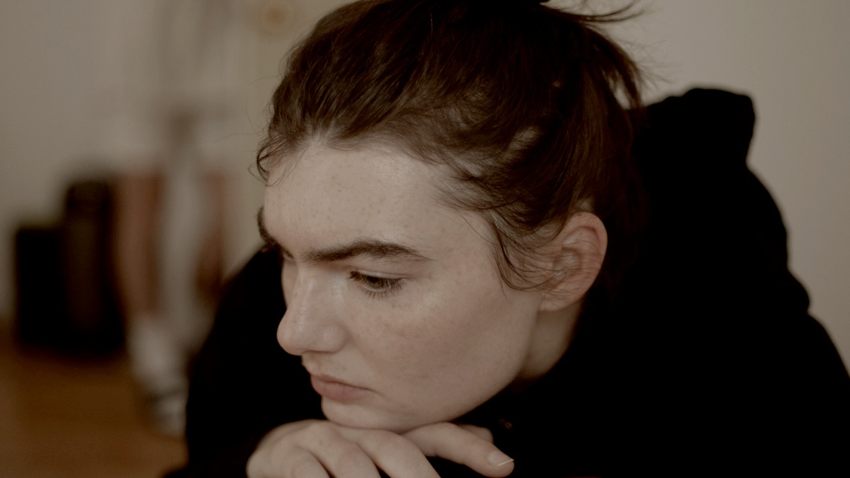
a woman sitting on a couch looking down leaning on her hands by Gabriel Ponton
