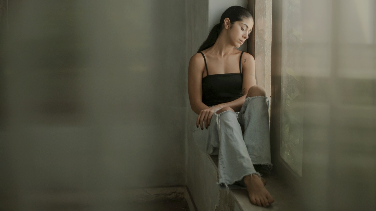 
A woman sitting on a ledge looking out a window
