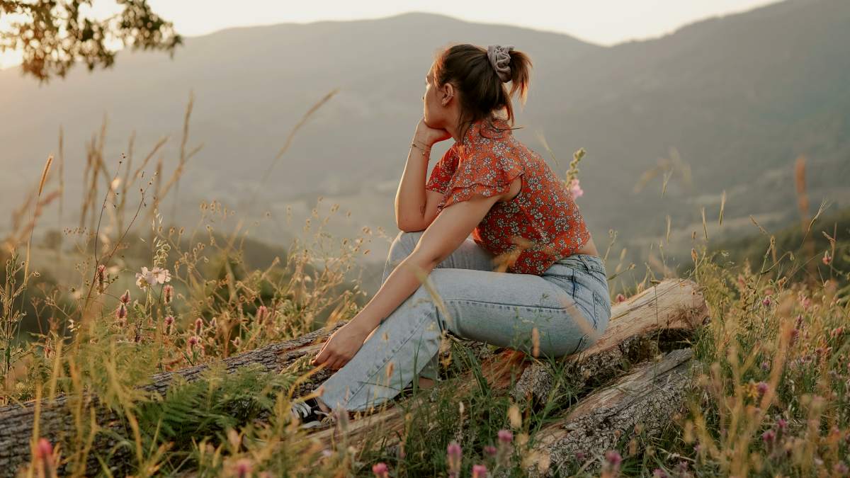 
a woman sitting on a rock staring into the distance
