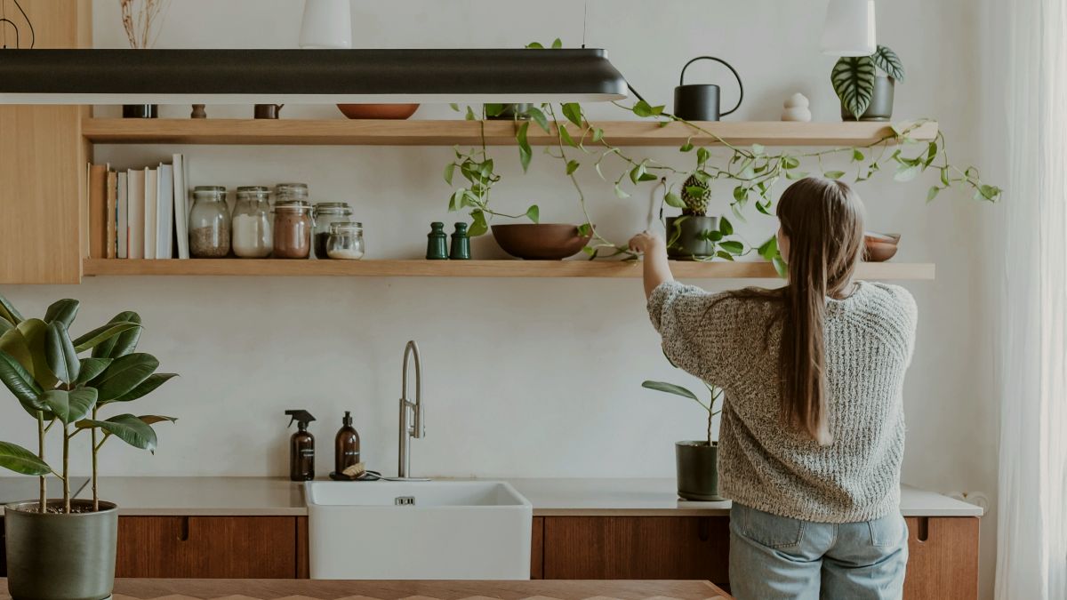 
a woman standing in a kitchen next tidying the shelves up
