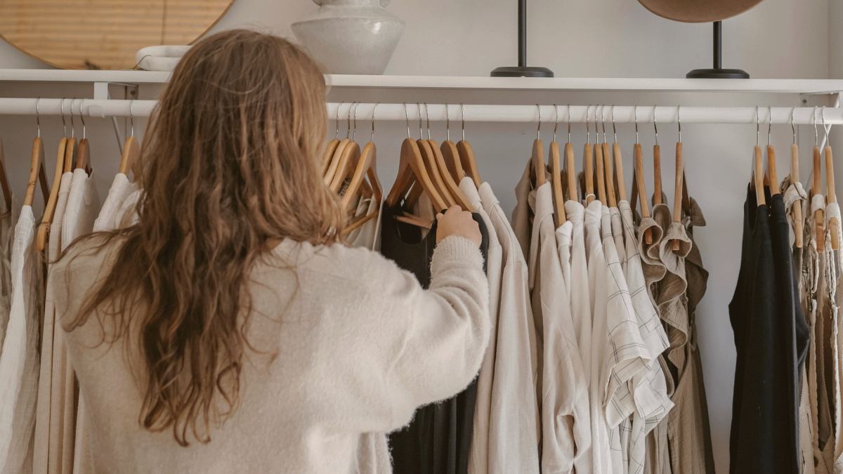 
a woman standing in front of a rack of clothes browsing the options
