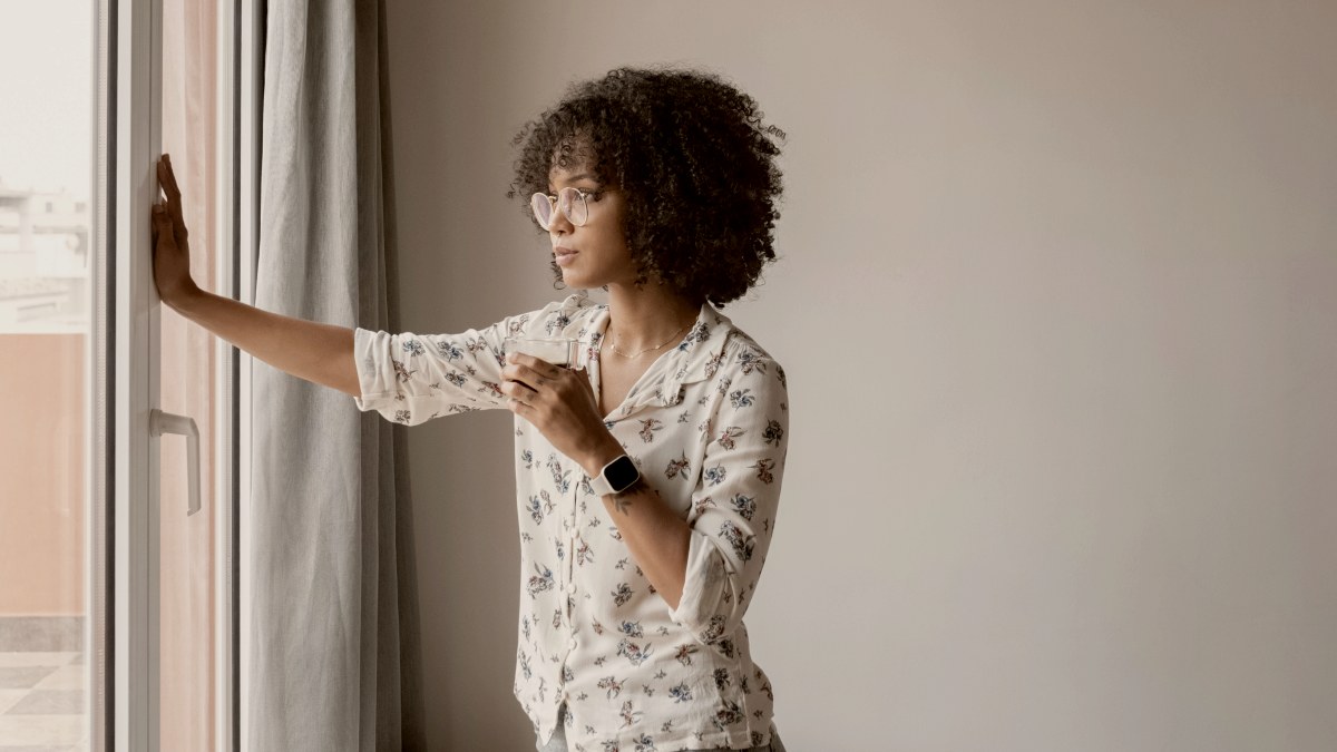 
a woman standing in front of a window holding a coffee cup by Milles Studio
