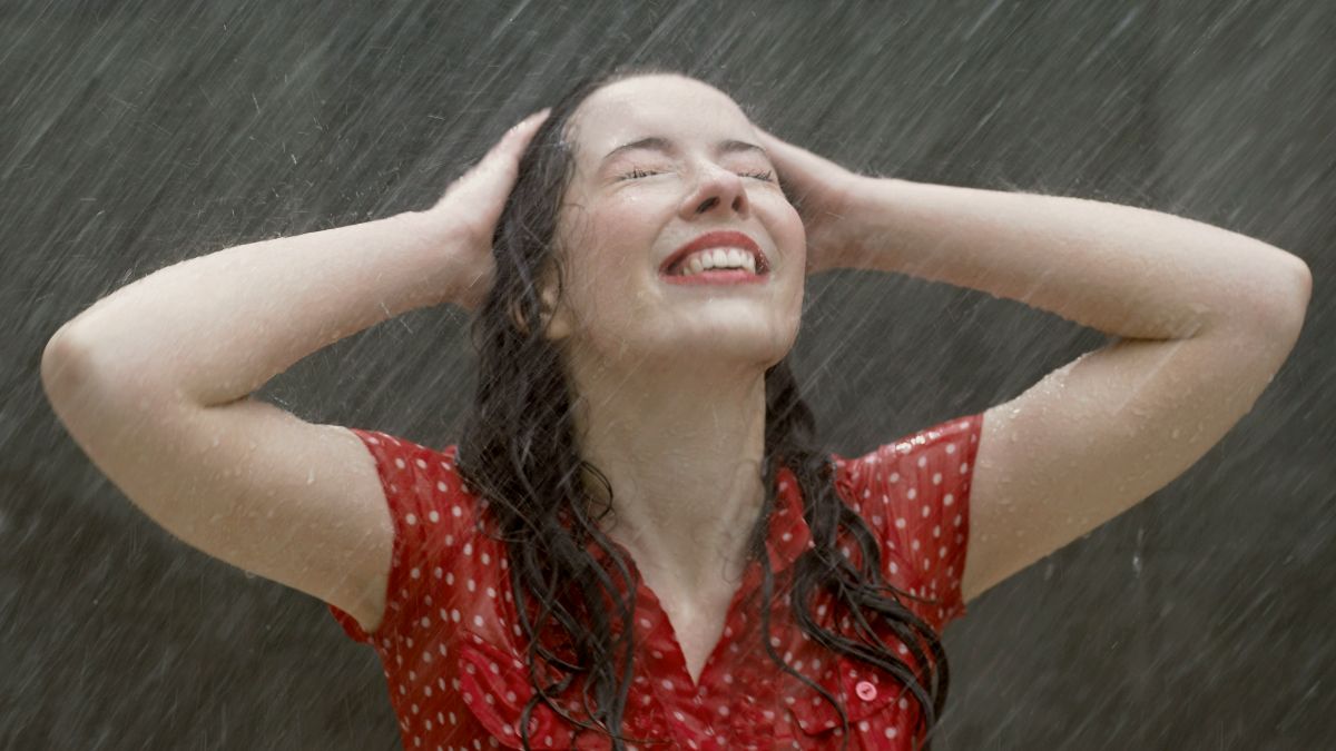 
a woman standing in the rain with her hands on her head
