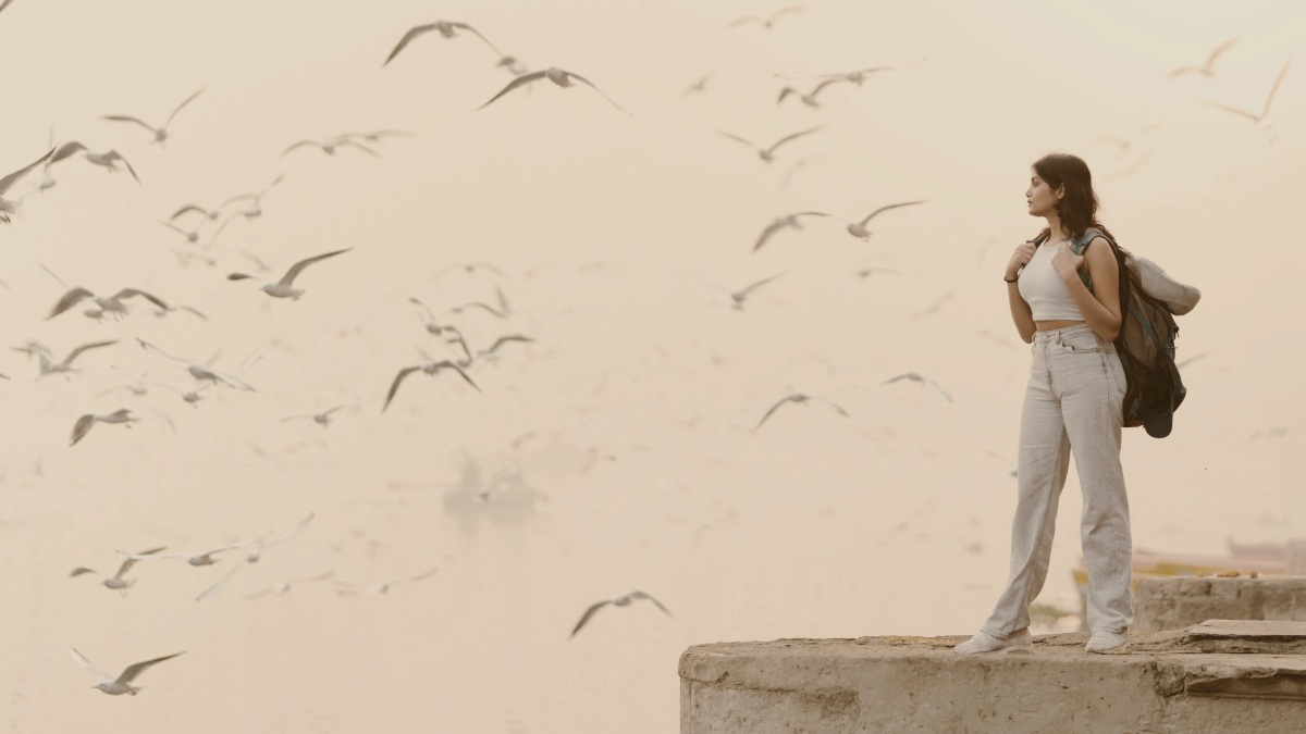 
A woman standing on a ledge with a flock of birds in the background by Aakash Malik

