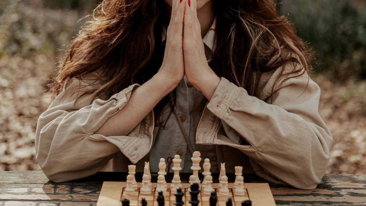 
a woman thinking while sitting in front of a chess board
