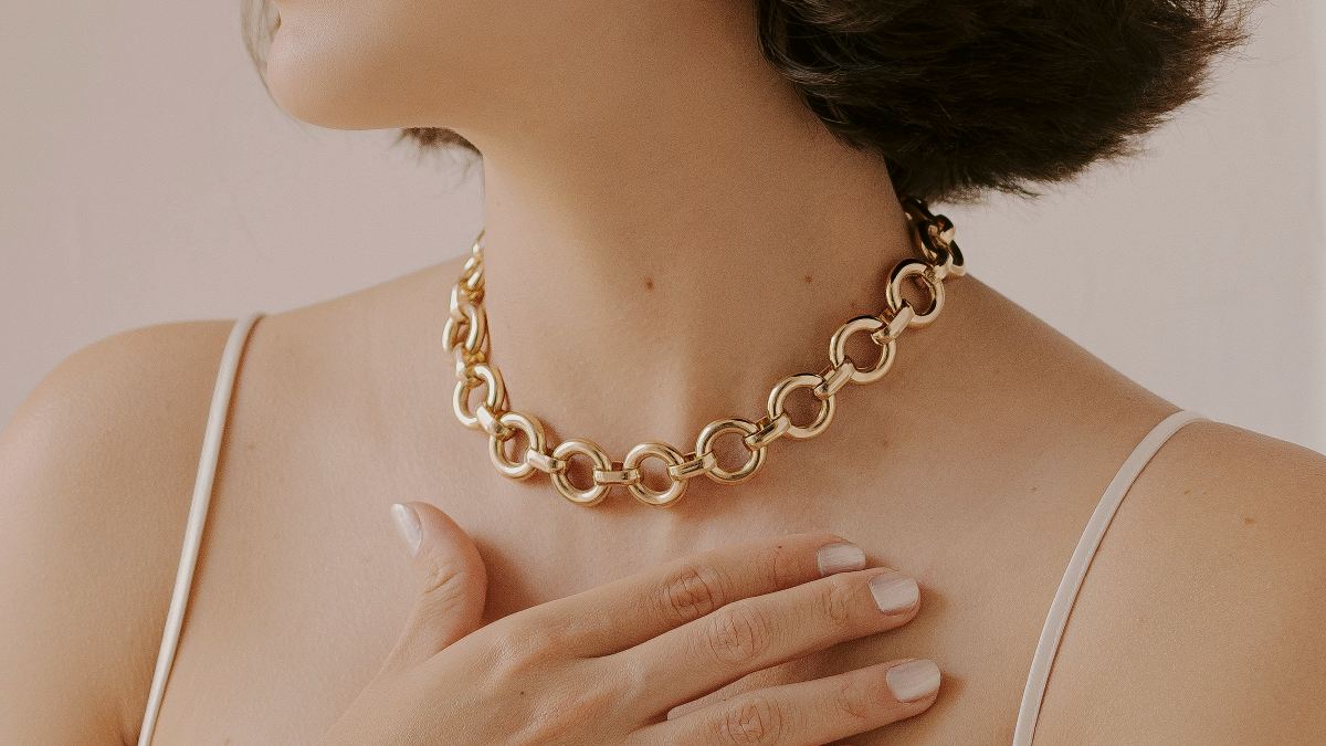 
A woman wearing a gold necklace and earrings
