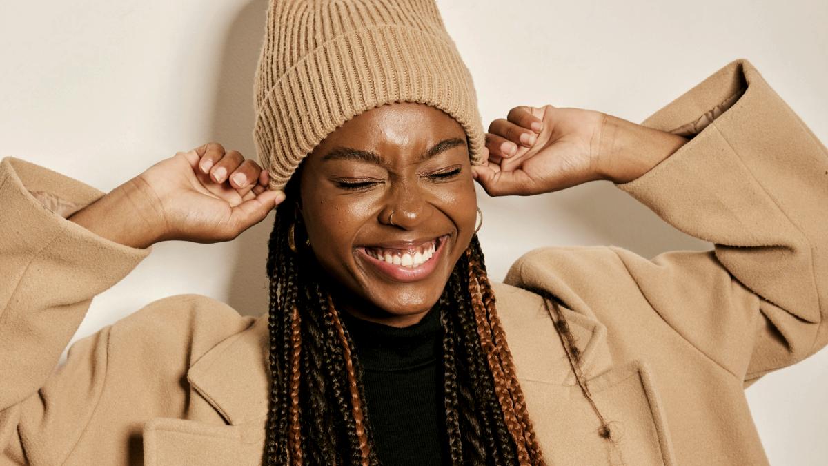 
a woman with braids and twists wearing a tan fall outfit
