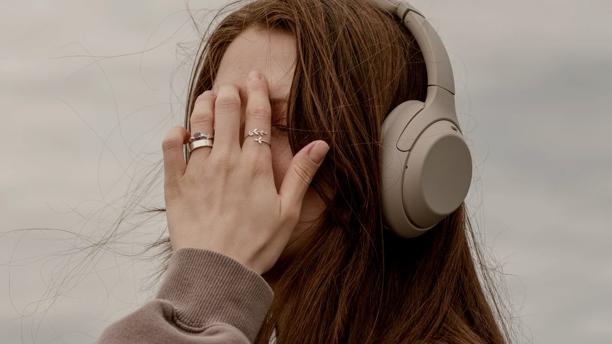 
a woman with headphones on her ears hand held up to her face by Valeriia Miller
