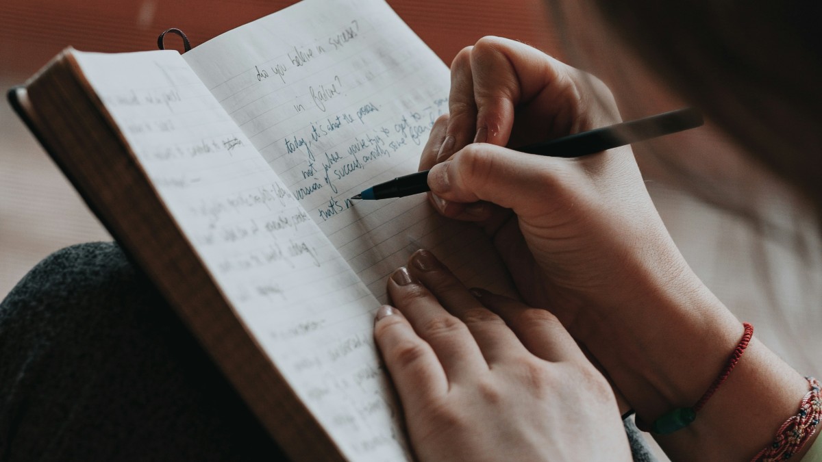 
a woman writing by hand in her journal and letting her personality show on the paper
