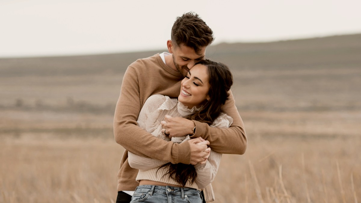 
A young man and woman hugging in a field
