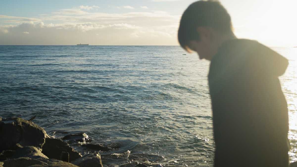 
a young man walking on a rocky path reflecting on his life and whether he is happy
