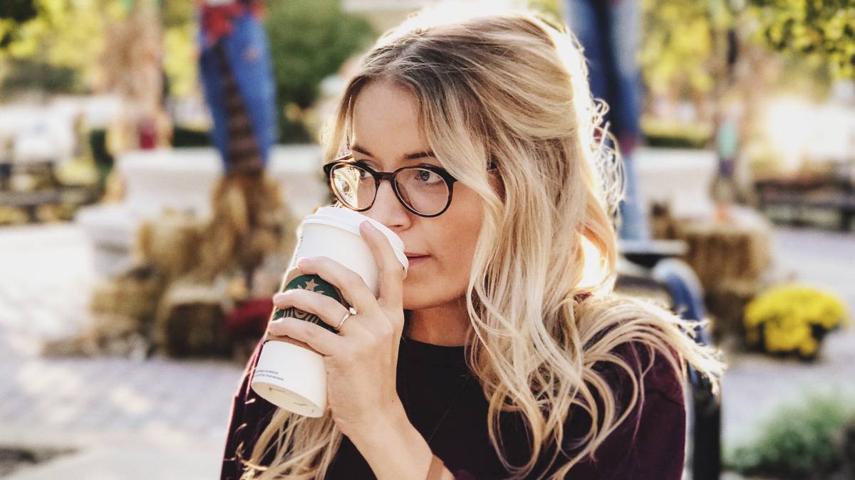 
a young woman drinking coffee and thinking about a passive agressive thing her friend did that upset her

