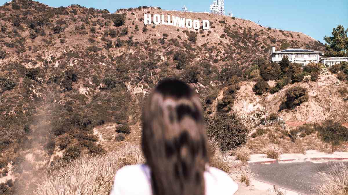
a young woman staring at the hollywood sign with fantasies in her mind

