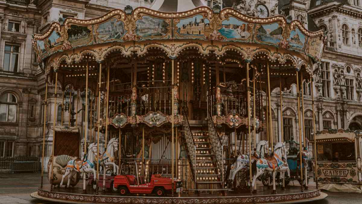 
an empty carousel in front of white concrete castle during daytime by Florian Olivo

