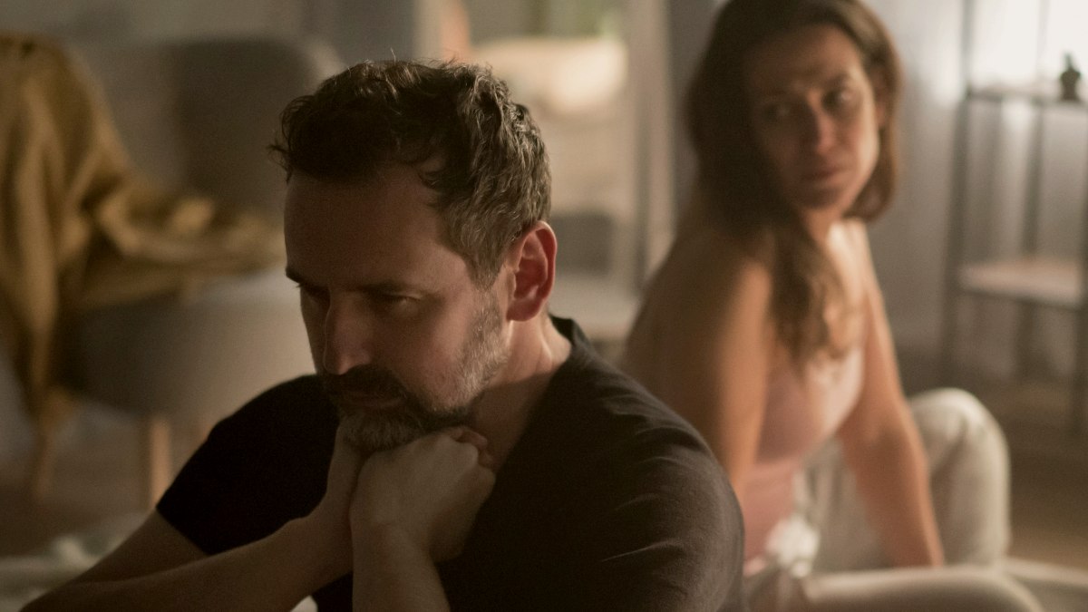 
An upset mature man with his wife in bed behind him relationship problems concept by getty images

