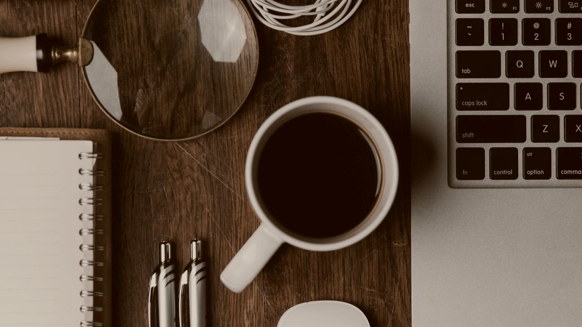 
arial photo of cup of coffee near MacBook Pro earphones pens and glasses by ian dooley
