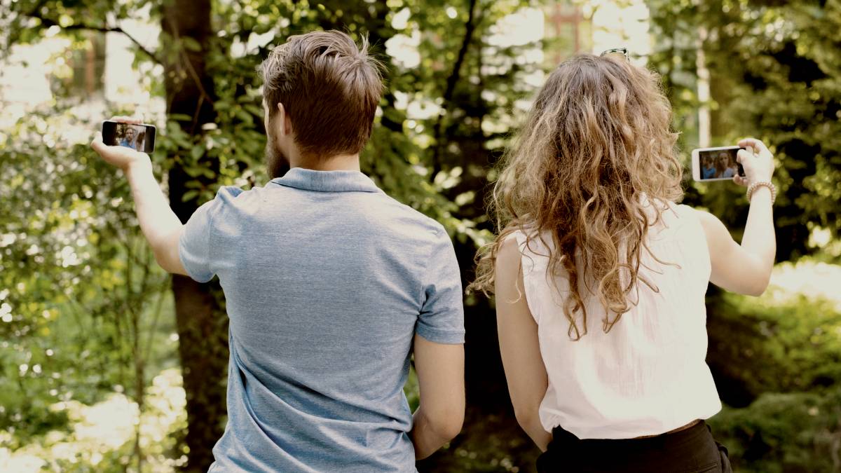
Beautiful young couple with smart phones sitting on concrete wall by Getty Images
