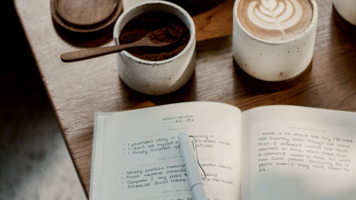 
black ballpoint pen on white ruled paper journal and coffee on the table by Prophsee Journals
