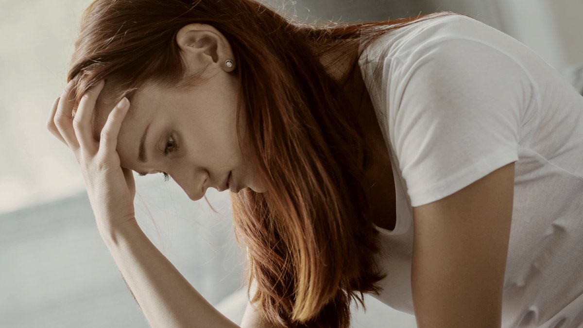 
Cheerless upset unhappy woman sitting on the sofa and holding her forehead while looking down by Getty Images
