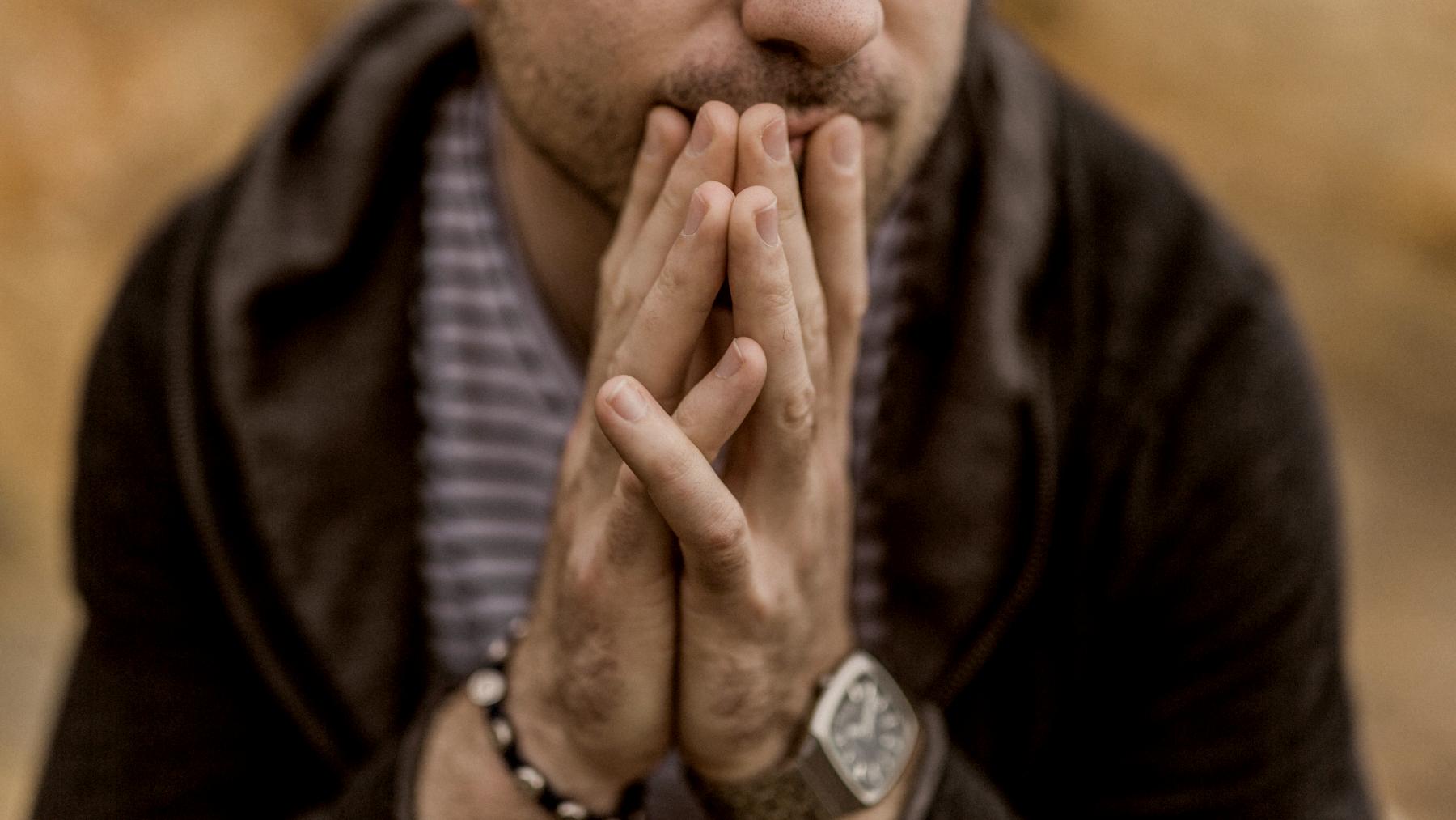 
close up of man hands holding his chin wearing watch by Nathan Dumlao
