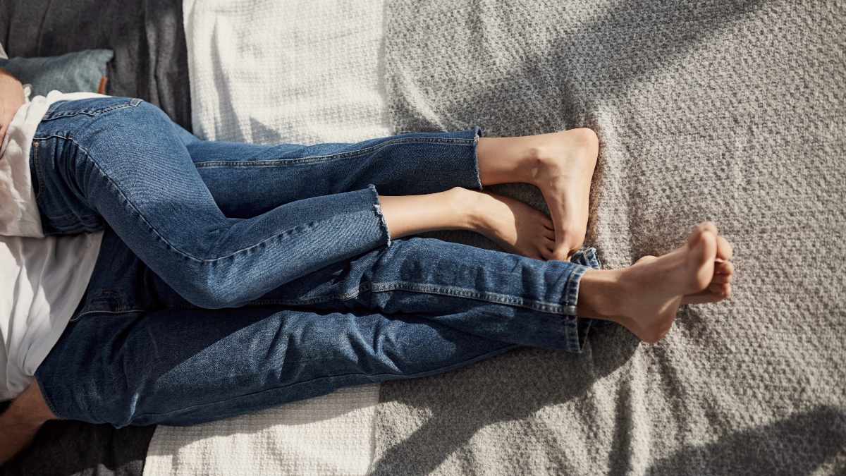 Close up view of young couple's legs on the bed at daytime with sunlight streaming in by Getty Images