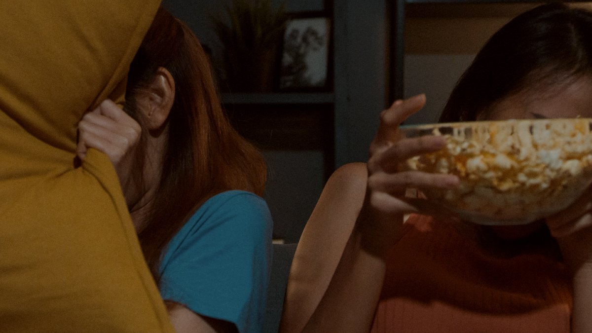 
couple ladies feel fear moment eat popcorn watch horror movie  on sofa in living room at home dark night by getty images
