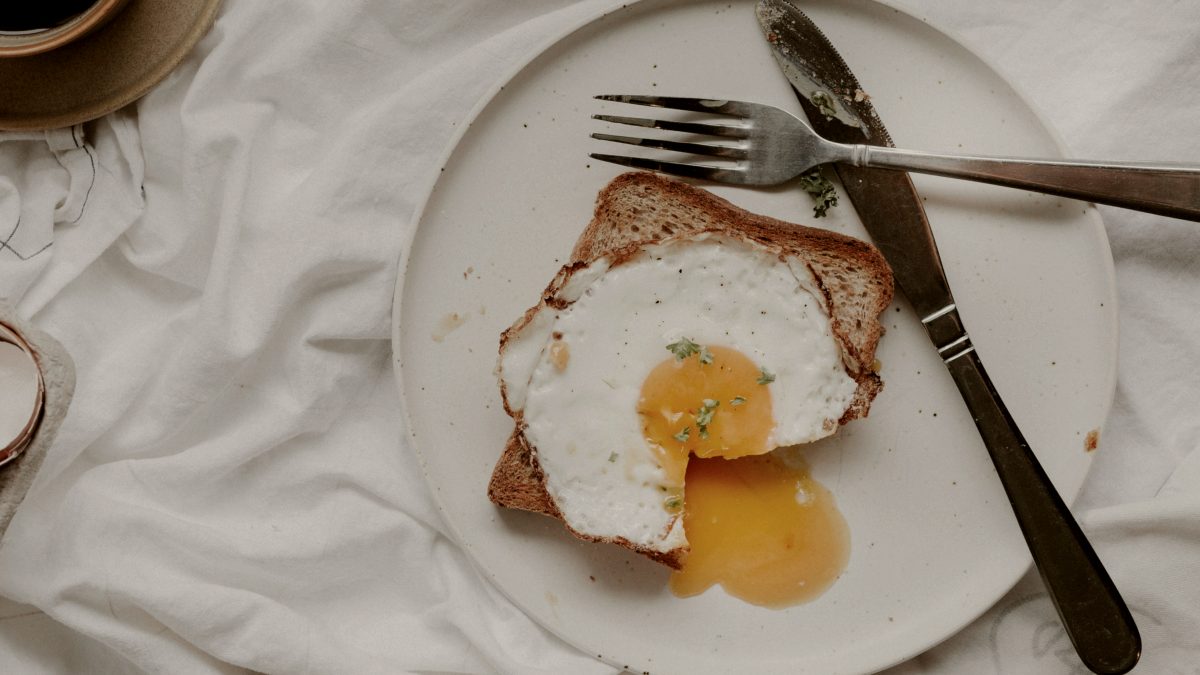 
egg on white ceramic plate beside stainless steel fork and knife
