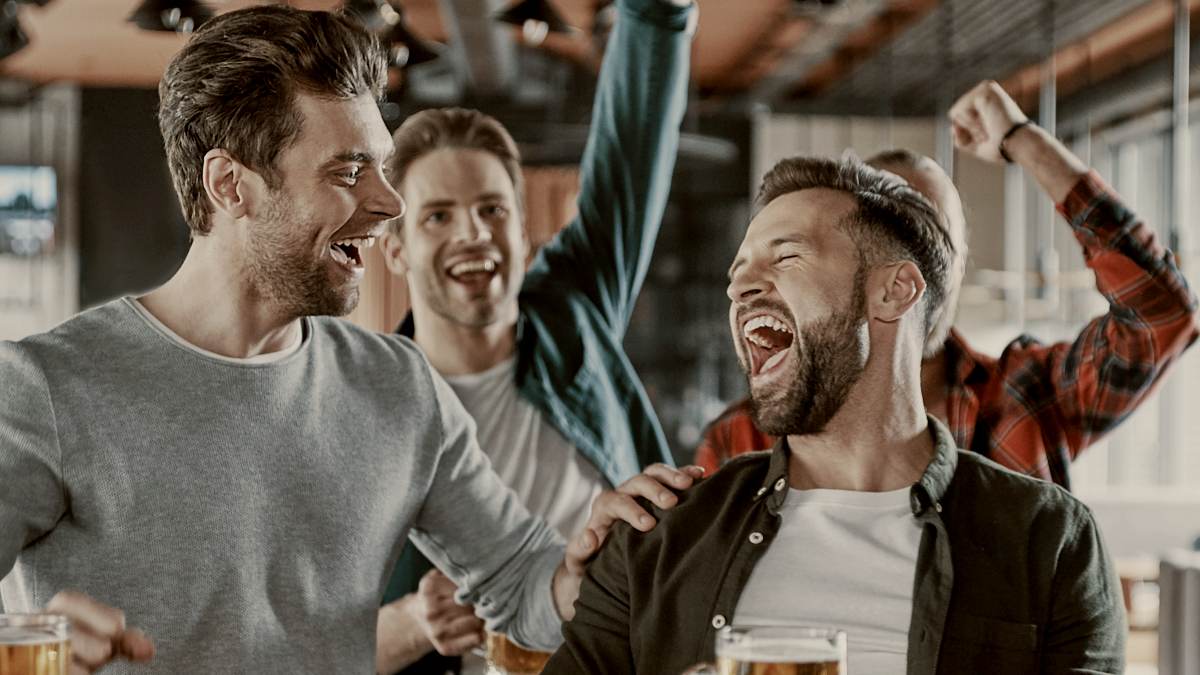 
Excited young men in casual clothing drinking beer and watching sport game while sitting in the pub by getty images
