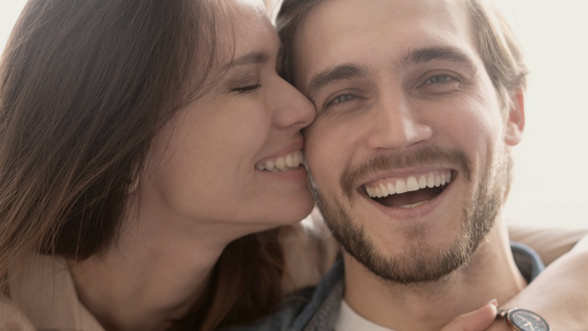 
Happy couple hugging and laughing in a couch at home by Getty Images
