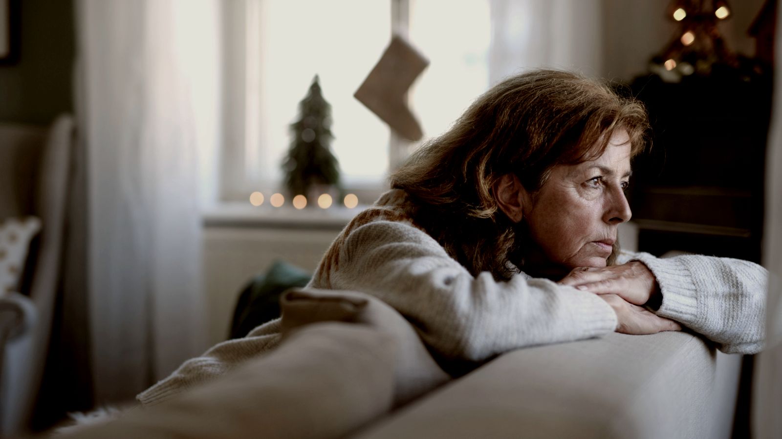 
lonely senior woman sitting on sofa indoors at Christmas by Getty Images
