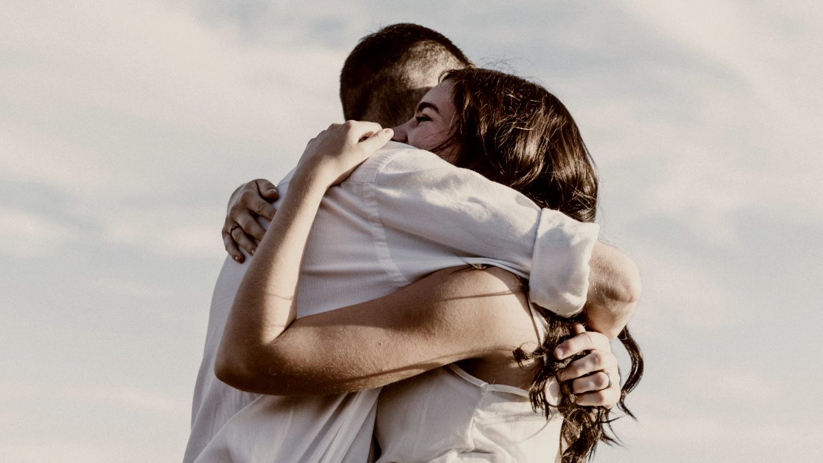 
man and woman hugging each other outside both wearing white by Priscilla Du Preez
