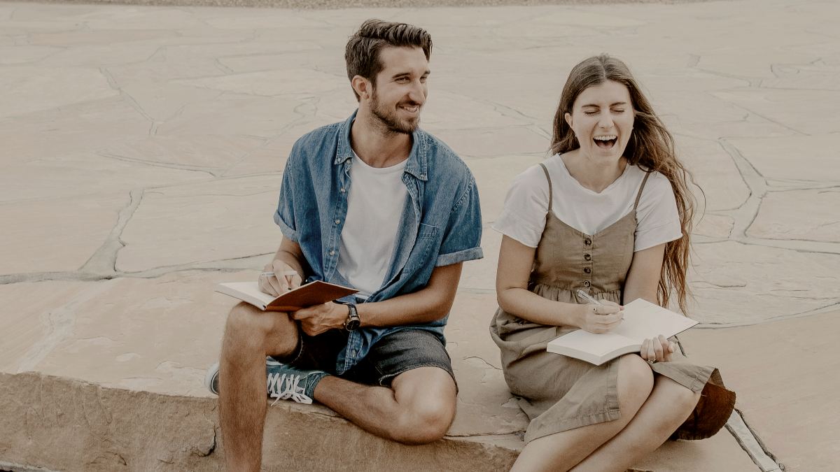 
man-and-woman-sitting-side-by-side-holding-notebooks
