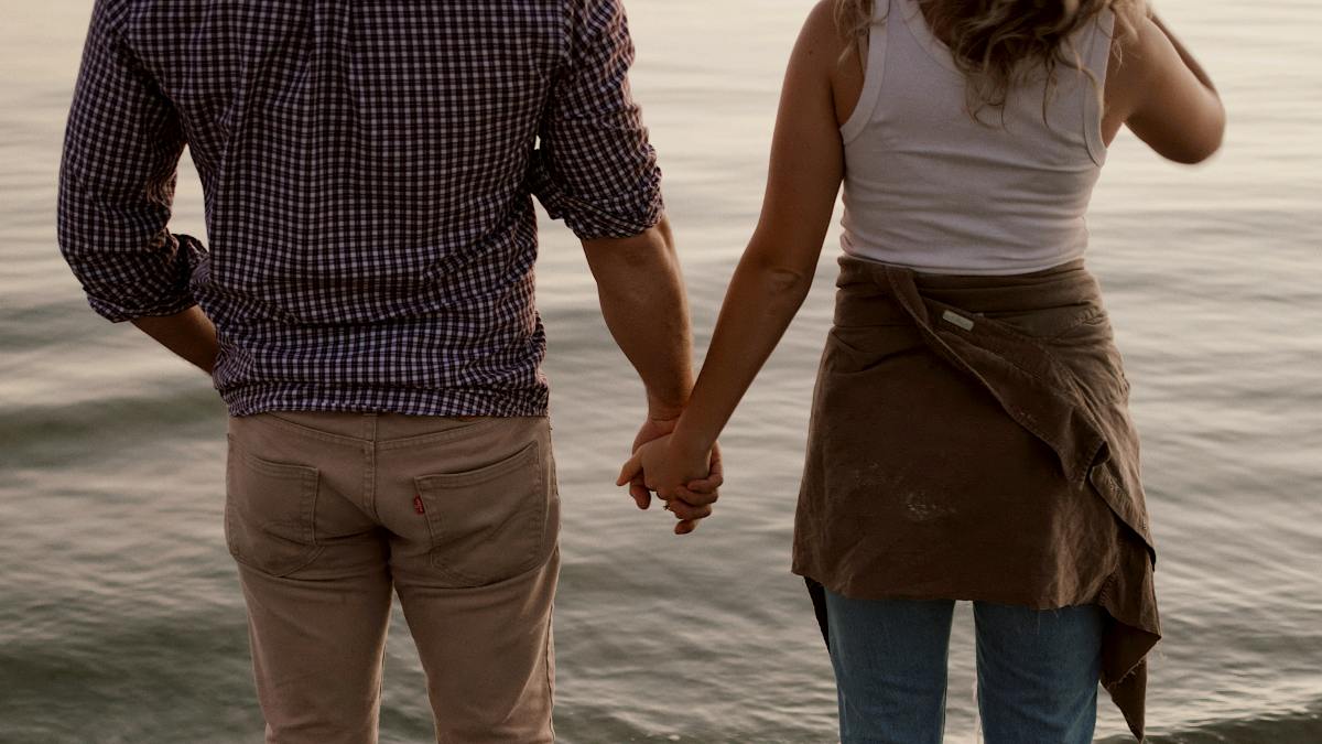 
man and woman standing barefoot on beach holding hands during daytime
