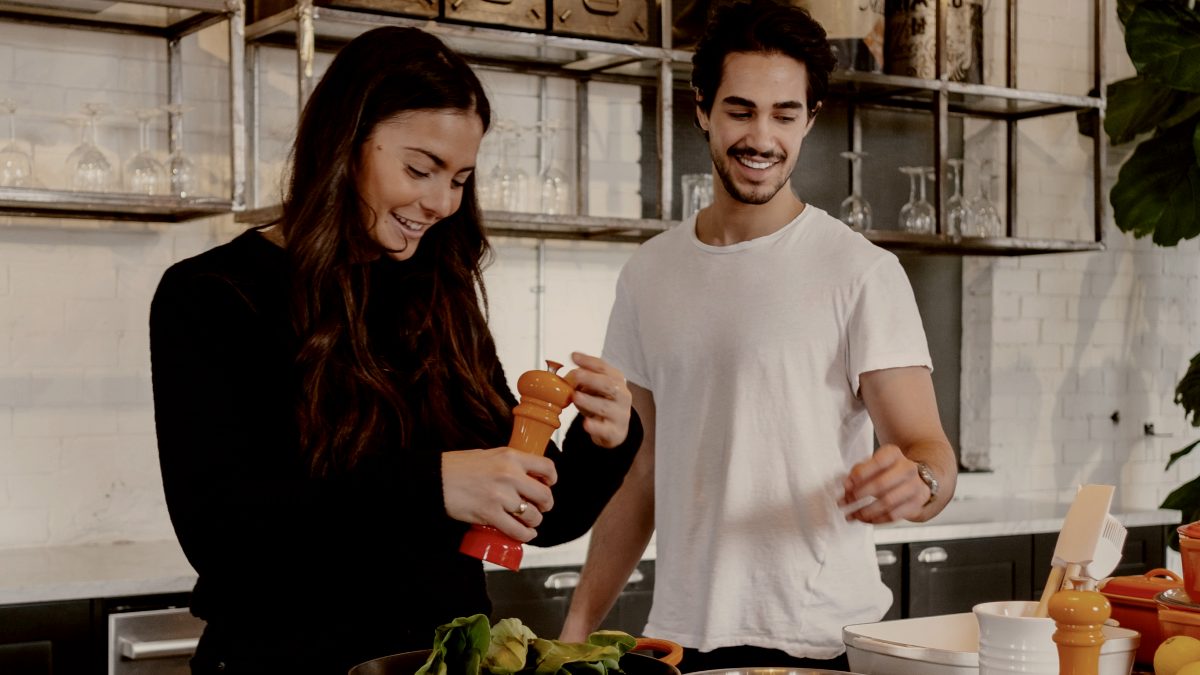 
man and woman standing in front of kitchen counter making a salad by jason briscoe

