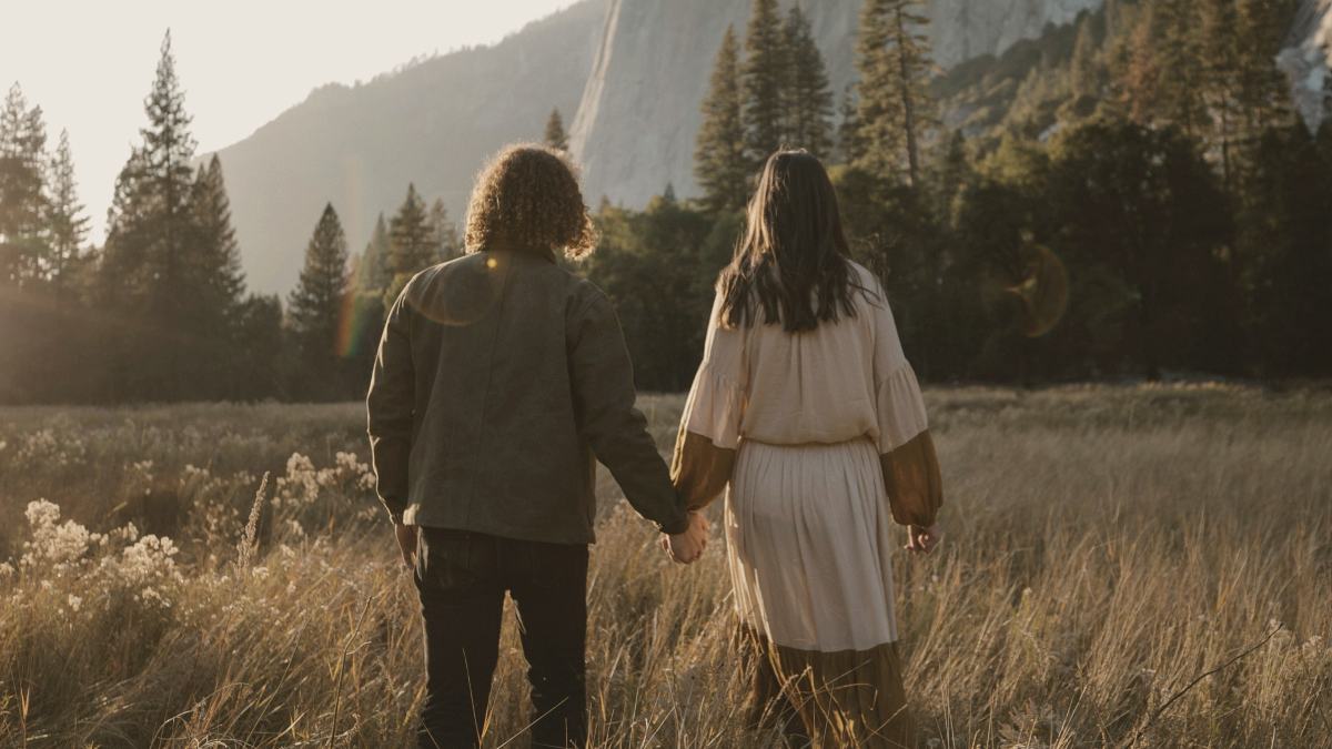 
man and woman standing on brown grass field near white mountain during daytime
