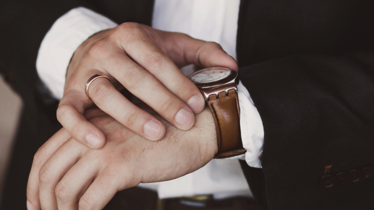 
Man in black suit checks new brown watch by Getty Images
