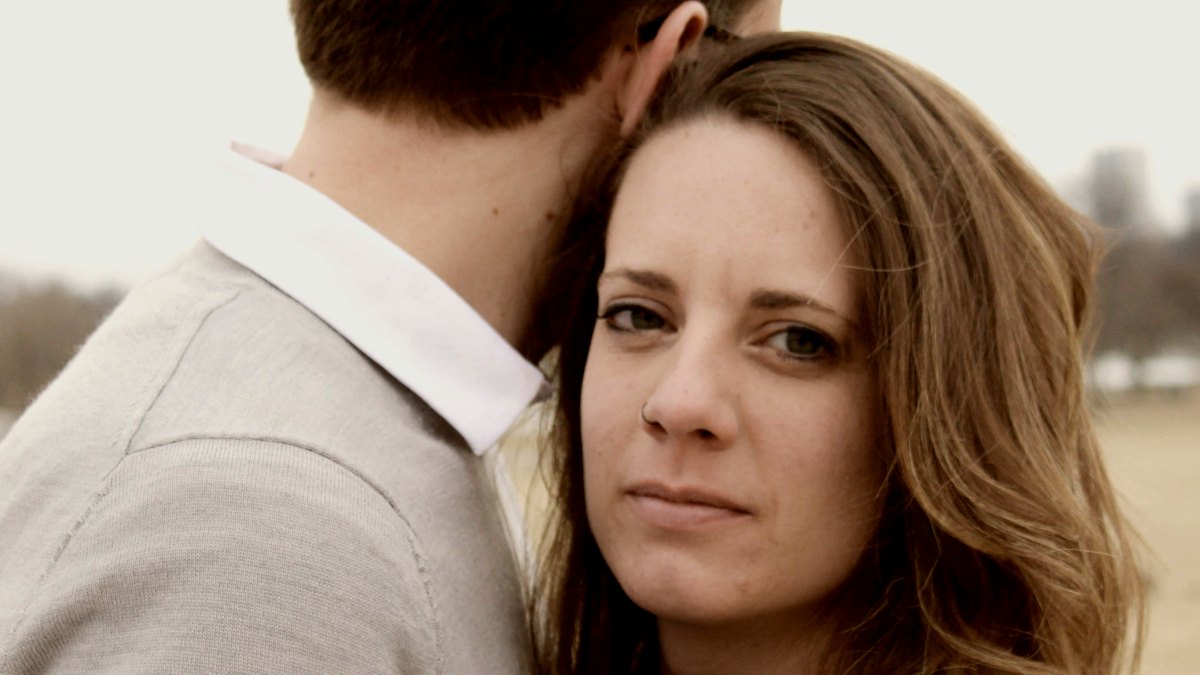 
man in grey and white collared shirt looking away and woman in black top looking at the camera by KaLisa Veer
