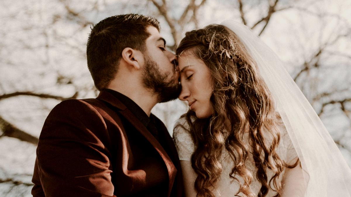 
man-kissing-woman-on-forehead-near-bare-tree-during-daytime
